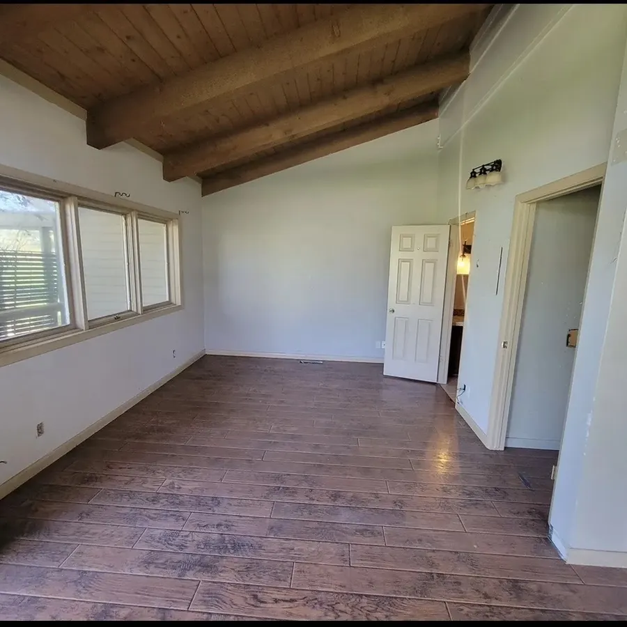 Before: a finished Park City room with a vaulted wood-plank ceiling, white drywall walls, baseboards and finished flooring